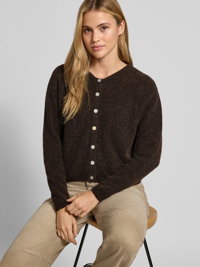 Kobieta prezentuje kardigan Relaxed Fit Cardigan aus Woll-Alpaka-Mix Model 'VITOW' od American Vintage, imitacja dzianiny, listwa guzikowa, okrągły dekolt, ciemny brąz, długość tyłu 52 cm, długość rękawów 56 cm, Ganzkörperansicht z przodu