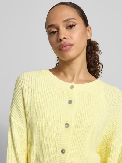 Frauenmodel trägt Regular Fit Strickjacke aus Viskose-Mix Modell 'LENI' von VILLA SOPHIE in Gelb, feiner Strick, Nahaufnahme Oberkörper.