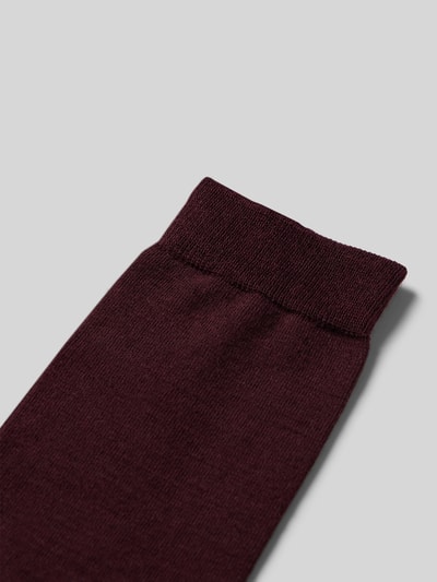 Produktfoto, Socken mit Label-Schriftzug Modell 'SOFTMERINO' von FALKE aus Schurwoll-Baumwoll-Mix mit Stretch-Anteil, elastisches Rippenbündchen, damen, weiche feine Textur in dunklem Bordeauxton.