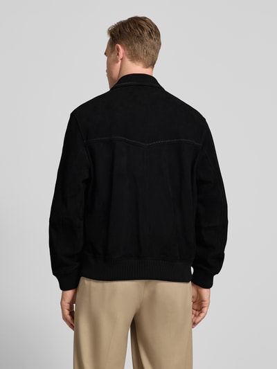 Mannelijk model draagt Super Slim Fit Lederjacke aus Ziegenleder Modell 'Lemai' van HUGO in suèdelook, zwart, achterpas, platte kraag, ritssluiting, labelopschrift, lange mouw met geribde mouwboord, rompzoom geribd, pattentas, materiaalverwerking echt geitenleer. Ganzkörperansicht van achteren.