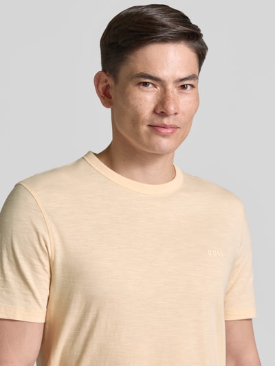 Männermodel trägt Regular Fit T-Shirt aus reiner Baumwolle Modell 'TEGOOD' von BOSS Orange, unifarben, Logo-Print, Nahaufnahme Oberkörper.