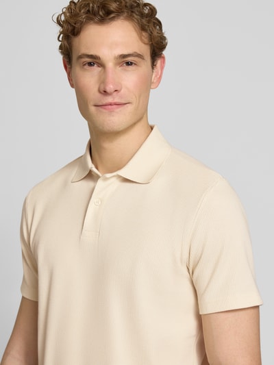 Männermodel trägt Regular Fit Poloshirt aus Baumwoll-Mix Modell 'BLAZE' von SELECTED HOMME in Beige, Piqué-Struktur, Nahaufnahme Oberkörper.