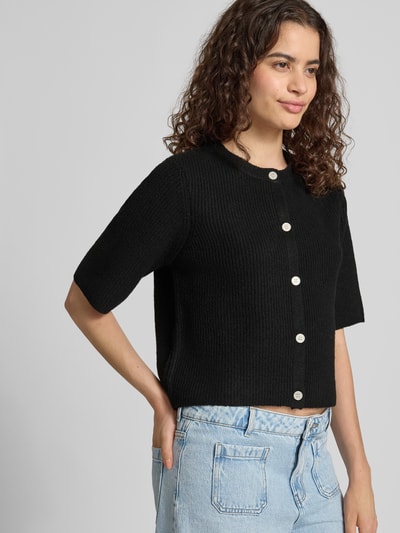 Frauenmodel trägt Boxy Fit Strickjacke aus Rippstrick Modell 'SILLY' von PIECES in Schwarz, Melange-Optik, Crew Neck, Nahaufnahme Oberkörper.