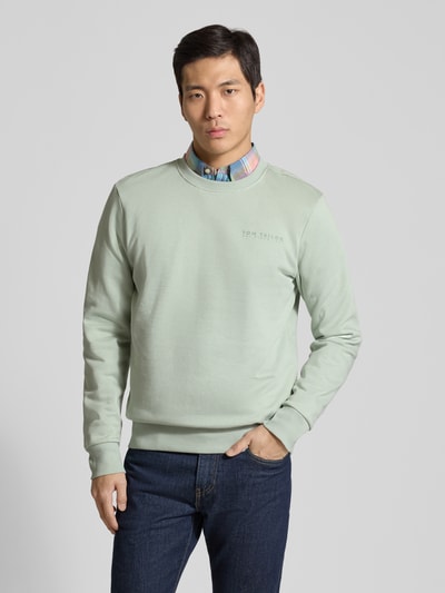 Męski model nosi Regular Fit Sweatshirt aus Baumwoll-Mix od Tom Tailor, efekt: jednolity kolor, nadruk z logo, dekolt okrągły, długi rękaw, zakończenia prążkowane, dzianina dresowa z mieszanki bawełny, całkowity widok z przodu