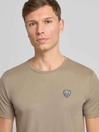 Männermodel trägt T-Shirt aus Viskose-Mix mit Label-Patch von EA7 Emporio Armani, Slim-Fit, Rundhalsausschnitt, Nahaufnahme Oberkörper.