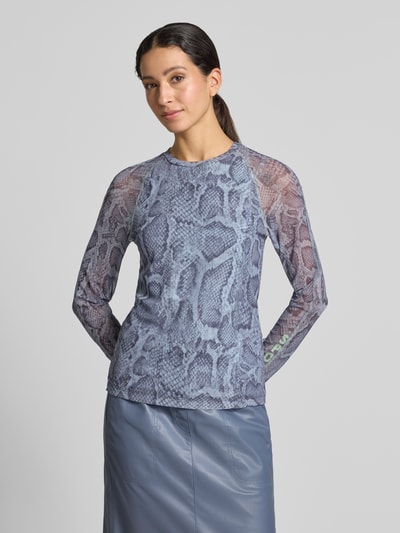 Frauenmodel trägt Longsleeve aus Mesh mit Schlangen-Muster von Marc Cain in Blau-Grau, körpernaher Schnitt, Ärmel semitransparent, Nahaufnahme Oberkörper.