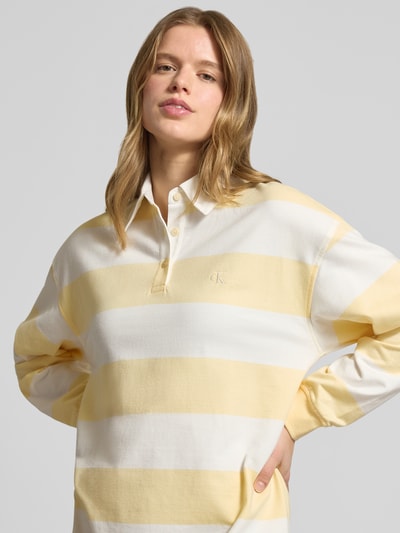 Frauenmodel trägt Regular Fit Minikleid mit Polokragen Modell 'Varsity' von Calvin Klein Jeans in Reine Baumwolle, gelb-weiße Streifen, Langärmelig, Logo-Stitching, Elastische Ärmelabschlüsse, Nahaufnahme Oberkörper.