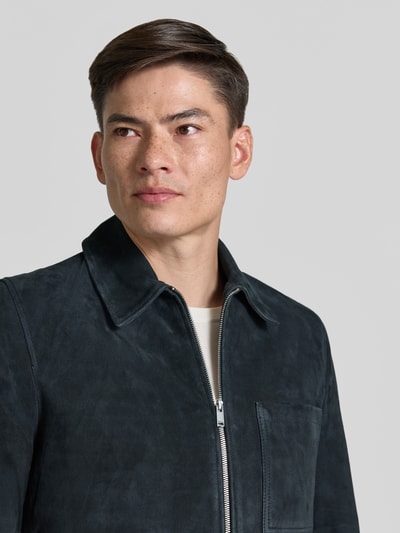 Męski model nosi czarną skórzaną kurtkę z zamkiem, kołnierzem i kieszenią na piersi, Lederjacke mit Reißverschluss Modell 'JERSON' od Drykorn, krój regular fit, zbliżenie na górną część ciała.