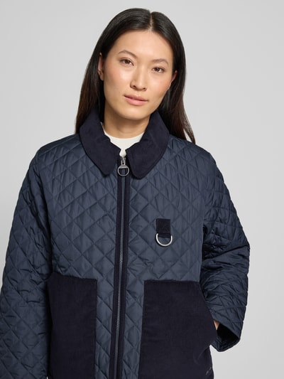 Kobiece model prezentuje granatową kurtkę pikowaną Barbour Regular Fit Steppjacke mit aufgesetzten Seitentaschen Modell 'AYLESBY', teksturowane powierzchnie, detaliczne przeszycia, zbliżenie na górną część ciała, damska kurtka pikowana, Ganzkörperansicht von vorne.