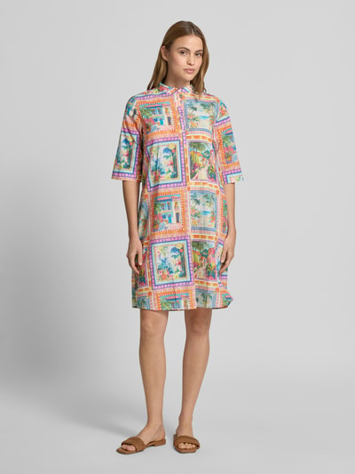 Frauenmodel trägt Knielanges Kleid aus reiner Viskose von Emily Van den Bergh mit buntem Print, Stehkragen, Knopfleiste, 3/4-Arm, lockere Passform, Ganzkörperansicht von vorne.
