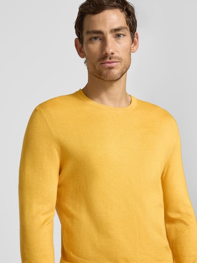 Männermodel trägt Strickpullover mit geripptem Rundhalsausschnitt von MCNEAL in Gelb, taillierte Passform, Nahaufnahme Oberkörper.