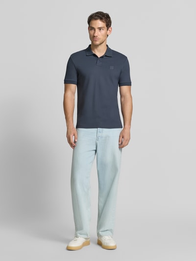 Männermodel trägt Regular fit poloshirt aus katoenmix model 'Passenger' van BOSS Orange, donkerblauw, met lichte jeans, Ganzkörperansicht von vorne.