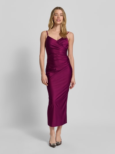 Frauenmodel trägt Cocktailkleid mit Spaghettiträgern und V-Ausschnitt von TROYDEN COLLECTION in Satin, körpernahe Schnittführung, Midikleid, glänzende Oberfläche, Farbe Lila, Rückseitiger V-Ausschnitt, Rückenreißverschluss, Rückenlänge 125 cm, Brustweite 37 cm, Ganzkörperansicht von vorne.