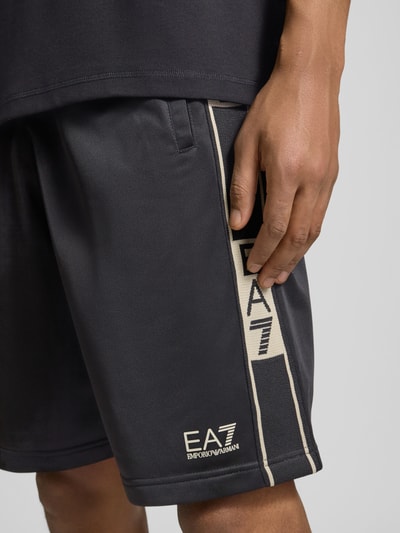 Männermodel trägt Shorts mit Logo und Eingrifftaschen von EA7 Emporio Armani, Relaxed-Fit, elastischer Bund, Nahaufnahme Oberschenkel.