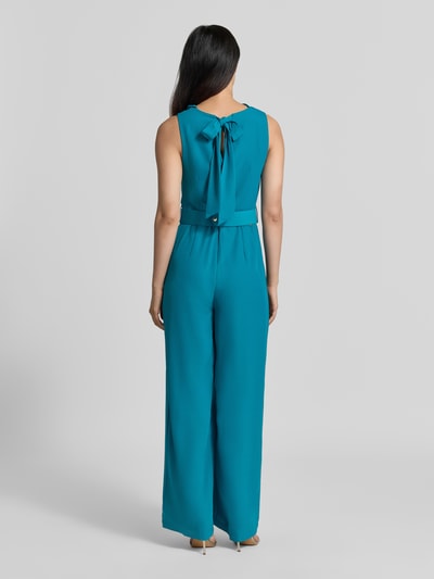Frauenmodel trägt Jumpsuit mit Neckholder von Rinascimento in Türkis, Material-Mix mit Stoffgürtel, taillierte Passform, Ganzkörperansicht Rückansicht.