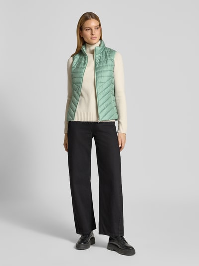 Vrouwenmodel draagt Regular Fit Bodywarmer met ritssluitingzakken van s.Oliver RED LABEL, effen look, opstaande kraag, doorgestikt materiaal, ganzebodyaanzicht van voren.