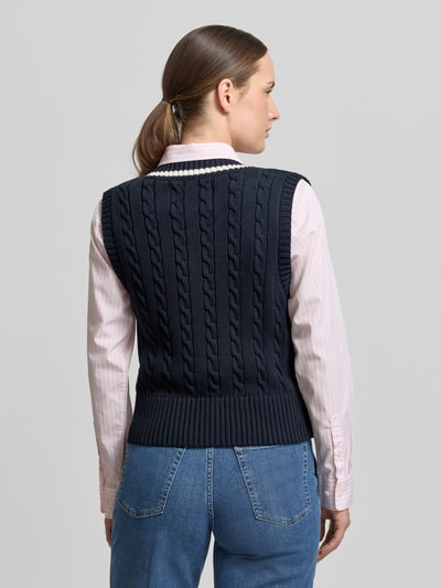 Kobiece model nosi bezrękawnik z dekoltem w serek i wyhaftowanym logo Pullunder mit V-Ausschnitt und Label-Stitching von Gant, bawełna, krój slim fit, ścieg warkoczowy, długość tyłu w rozmiarze S: 50 cm, całkowity widok z tyłu.