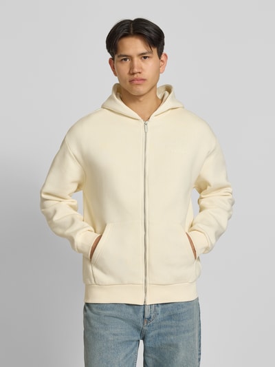 Męski model nosi bluza rozpinana z nadrukiem z logo od REVIEW, mieszanka bawełny, prosty krój, kaptur, zamek błyskawiczny, wpuszczane kieszenie, prążkowane wykończenia, długość tyłu w rozmiarze M: 60 cm, długość rękawów: 63 cm, jasny kolor, gładka tekstura, widok z przodu, ujęcie całej sylwetki.