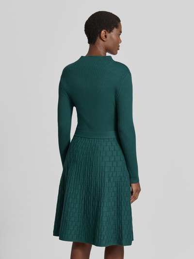 Männermodel trägt Knielanges Strickkleid mit Bindegürtel von Apricot, Mieszanka wiskozy, linia a, długość do kolan, stójka, wiązany pasek, długość tyłu w rozmiarze S: 103 cm, szerokość w rozmiarze S: 38 cm, długość rękawów w rozmiarze S: 59 cm, zielony, struktura prążkowana i fakturowana, Ganzkörperansicht Rückansicht