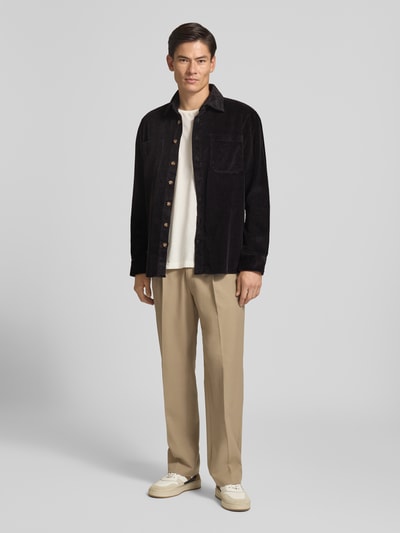 Männermodel trägt Regular Fit Hemdjacke aus Cord mit Kentkragen von Christian Berg Men in Schwarz, kombiniert mit heller Hose, Ganzkörperansicht von vorne.
