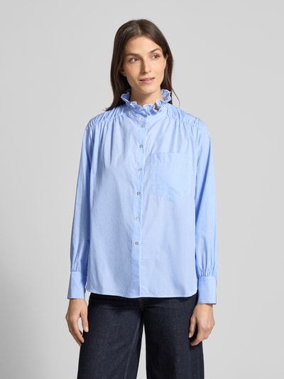 Modelka kobieca nosi Regular Fit Bluse aus reiner Baumwolle mit Stehkragen od Rich & Royal, jasnoniebieska, pionowe paski, falbany, długi rękaw, kieszeń na piersi, pełna listwa guzikowa, krój regular fit, bawełna, widok całej sylwetki z przodu.