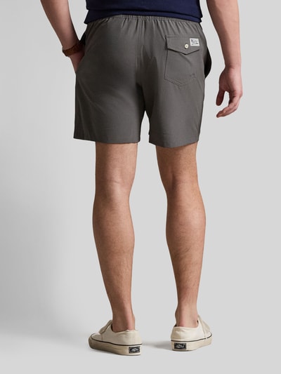 Männermodel trägt Badeshorts mit Logo-Stitching Modell 'TRAVELER' von Polo Ralph Lauren Underwear in Unifarben, Gesäßtasche, Ganzkörperansicht Rückansicht.