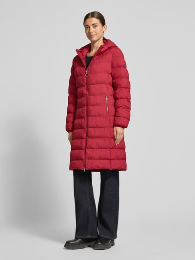 Frauenmodel trägt Regular Fit Steppmantel mit Kapuze Modell 'Famalia-4' von HUGO, unifarben matt, Longline, Ganzkörperansicht von vorne.