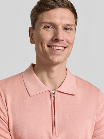 Männermodel trägt Regular Fit Poloshirt aus reiner Wolle Modell 'TRAY' von SELECTED HOMME in Rosa, Strick, Nahaufnahme Oberkörper.