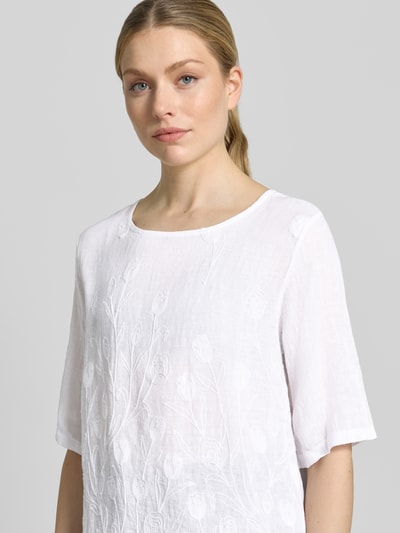 Frauenmodel trägt Blusenshirt mit Stitchings Modell 'No44raa' von ZABAIONE in Weiß, entspannter Schnitt, Nahaufnahme Oberkörper.