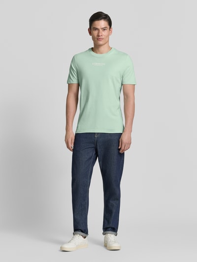 Männermodel trägt Regular Fit T-Shirt aus reiner Baumwolle von s.Oliver RED LABEL in Optik: Unifarben, Label-Schriftzug, Jersey, Ganzkörperansicht von vorne.