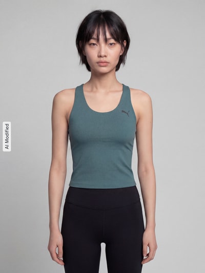 Frauenmodel trägt Slim Fit Sport-Top mit Logo-Print von PUMA in Dunkelgrün und Schwarz, Damen Sport-Top von PUMA Performance, Ganzkörperansicht von vorne.