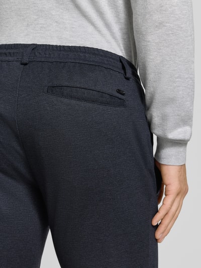 Männermodel trägt Tapered Fit Jogpants mit Viskose-Anteil Modell 'Phil' von Brax in dunklem Blau, Herren Weite Hose, Nahaufnahme Rückansicht.