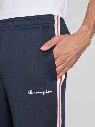 Männermodel trägt Sweatpants mit Bordüre von Champion in Dunkelblau mit weiß-roten Streifen, Baumwoll-Mix, Nahaufnahme Oberkörper