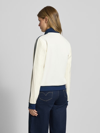 Frauenmodel trägt Strickjacke mit Reißverschluss von adidas Originals in Creme und Dunkelblau, Baumwoll-Mix mit Rippbündchen, lockerer Schnitt, Rückenlänge 59 cm, Ganzkörperansicht Rückansicht.