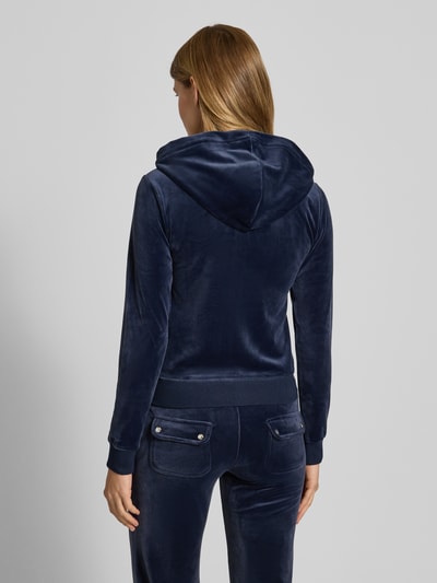 Frauenmodel trägt Sweatjacke mit Label-Stitching Modell 'ROBERTSON' von Juicy Couture in Dunkelblau, Material-Mix mit Stretch-Anteil, Regular Fit, Kapuze mit Tunnelzug, Rückansicht.