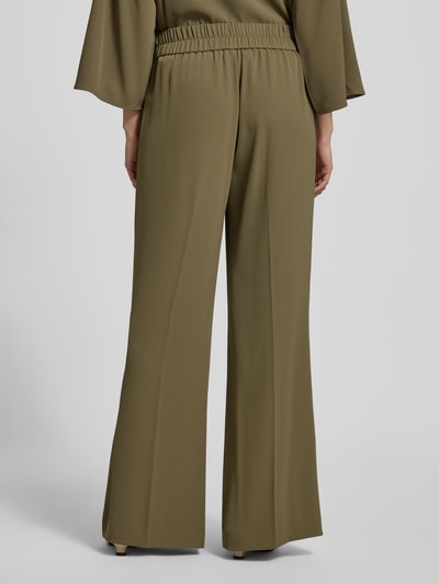 Vrouwenmodel draagt stoffen broek met elastische materiaalmix, flared fit, elastische band, siernaden, comma, ganzekörperaanzicht achteraan.