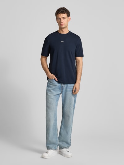 Männermodel trägt T-Shirt mit Label-Print von BOSS in Dunkelblau, Baumwoll-Elasthan-Mix, Regular Fit, Rundhalsausschnitt, Ganzkörperansicht von vorne. Rückenlänge bei Größe M: 70 cm.
