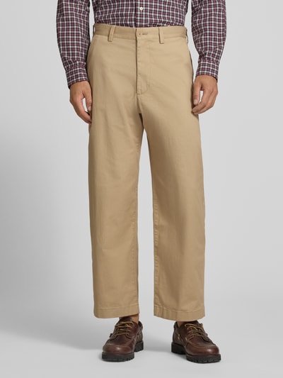 Männermodel trägt Loose Fit Weite Hose aus Baumwoll-Mix von Lacoste in Beige, strukturierte Oberfläche, Ganzkörperansicht von vorne. Herren Weite Hose von Lacoste