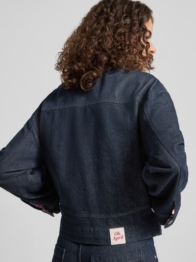 Frauenmodel trägt Regular Fit Jeansjacke mit aufgesetzten Taschen Modell 'Clara' von OH APRIL in dunklem Denim, Rückenansicht, reine Baumwolle, sichtbare Nähte, strukturierte Textur