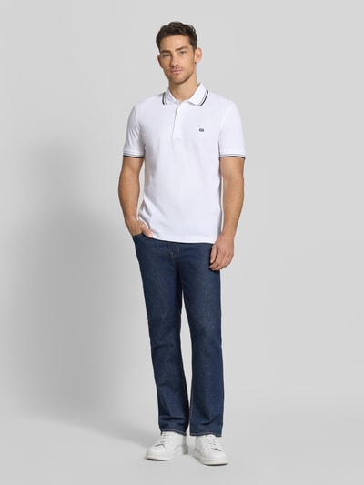 Männermodel trägt Regular Fit Poloshirt mit Kontraststreifen von Christian Berg Men aus reiner Baumwolle, Knopfleiste, weiße Farbe, Ganzkörperansicht von vorne. Rückenlänge bei Größe M: 71 cm.