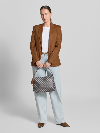 Frauenmodel trägt Shoulder Bag mit Innenfach Modell 'PORTA' von MANGO mit Allover-Label-Print, hellbraun-graue Farben, Ganzkörperansicht von vorne.