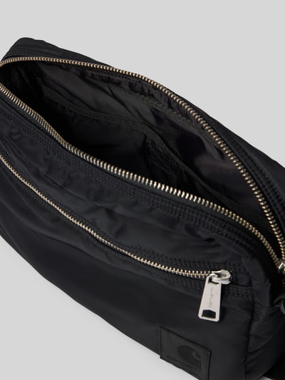 Produktfoto, Tasche mit Logo-Print von Carhartt Work In Progress in Schwarz, glatte wasserabweisende Oberfläche, silberner Reißverschluss, zeigt Hauptfach und Logo-Patch, Hauptfach mit Reißverschluss, verstellbarer Schulterriemen, Maße 28 x 21 x 7 cm, Schulterriemen 126 cm.
