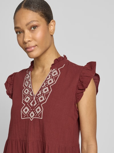Frauenmodel trägt figurumspielendes Freizeitkleid aus reiner Baumwolle Modell 'Dichte' von Vero Moda in Uni-Bordeauxrot, Flammgarn-Textur, Zierstickerei, Nahaufnahme Oberkörper.