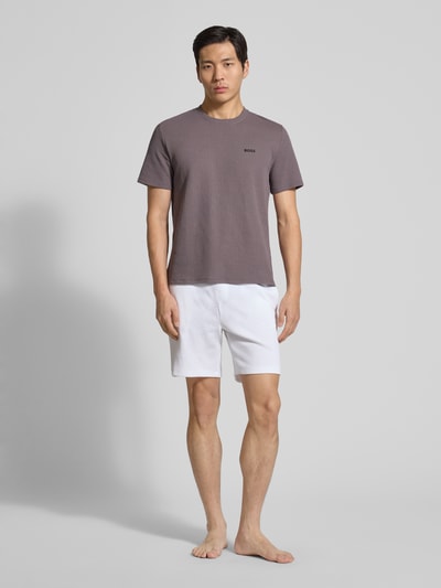 Männermodel trägt Regular Fit Pyjama-Oberteil aus Baumwoll-Mix Modell 'WAFFLE' von BOSS in Braun, unifarben, Kurzarm, Ganzkörperansicht von vorne.