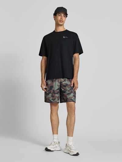 Männermodel trägt Oversized T-Shirt mit Logo-Stitching von KARL KANI, schwarze Farbe, Reine Baumwolle, Oversized-Fit, Rundhalsausschnitt, Rückenlänge bei Größe M 72 cm, Ganzkörperansicht von vorne.