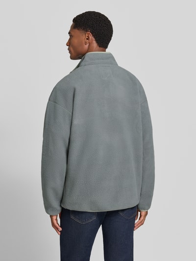 Männermodel trägt Fleecepullover mit Label-Patch Modell 'Helvetia™ II' von Columbia, prosty krój, stójka, długość tyłu 70 cm, długość rękawów 62 cm, widoczne tekstura polaru w szarym odcieniu, Ganzkörperansicht Rückansicht.