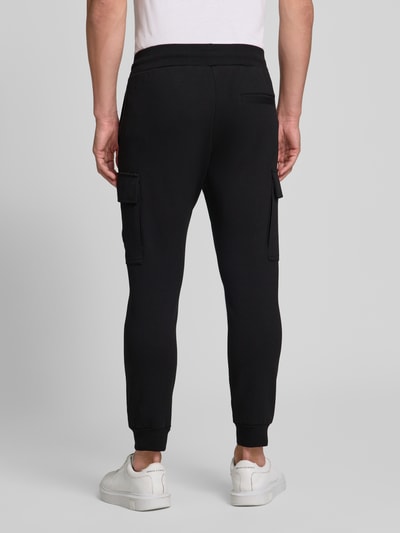 Männermodel trägt Regular Fit Sweatpants mit Cargotaschen von Antony Morato in Schwarz aus Baumwoll-Mix, Ganzkörperansicht Rückansicht.