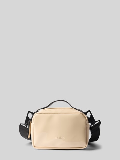 Produktfoto, beigefarbene Handtasche mit Reißverschluss Modell 'BOX BAG MICRO' von RAINS mit Label-Detail und verstellbarem Schulterriemen auf neutral grauem Hintergrund, glatte Textur