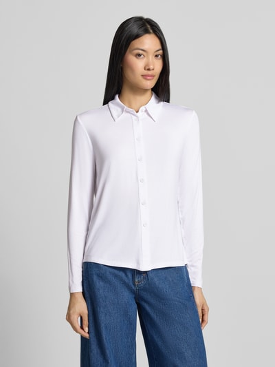 Frauenmodel trägt Slim Fit Hemdbluse aus Viskose-Mix von COMMA in Weiß mit durchgehender Knopfleiste und Hemdblusenkragen, glatte Textur, lange Ärmel, kombiniert mit blauer Jeans, Ganzkörperansicht von vorne. Rückenlänge 55 cm, Ärmellänge 58 cm.