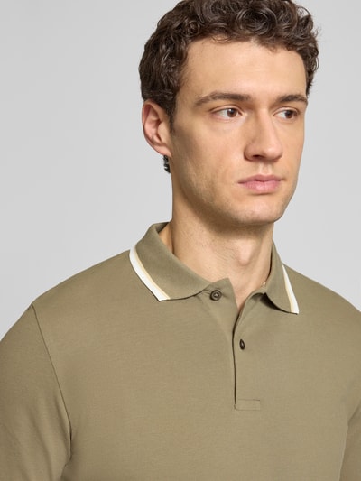 Männermodel trägt Slim Fit Poloshirt aus Bio-Baumwoll-Mix Modell 'SLIM ATLAS SPORT' von SELECTED HOMME in Unifarben, Nahaufnahme Oberkörper.